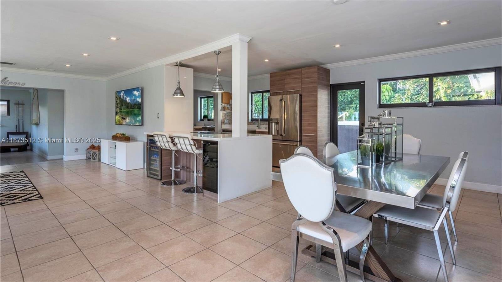 This open-concept kitchen and dining area features tile flooring, a breakfast bar, and stainless appliances — 201 NE 26th Ave, Pompano Beach FL 33062, POMPANO BEACH, FL