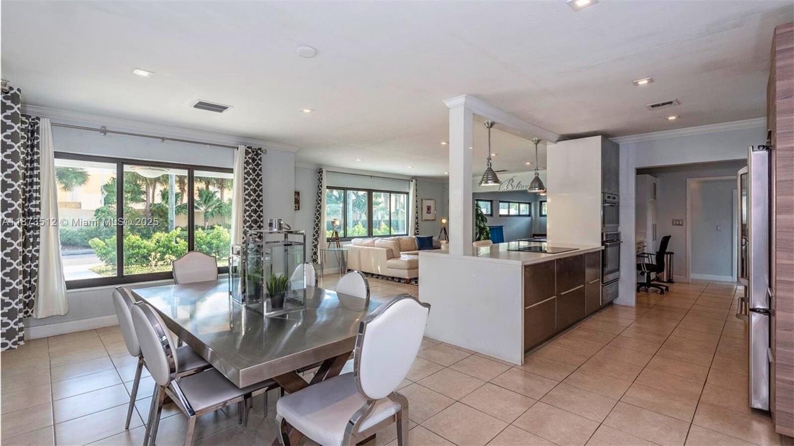 A dining area with a metal table sits adjacent to a kitchen and living room — 201 NE 26th Ave, Pompano Beach FL 33062, POMPANO BEACH, FL