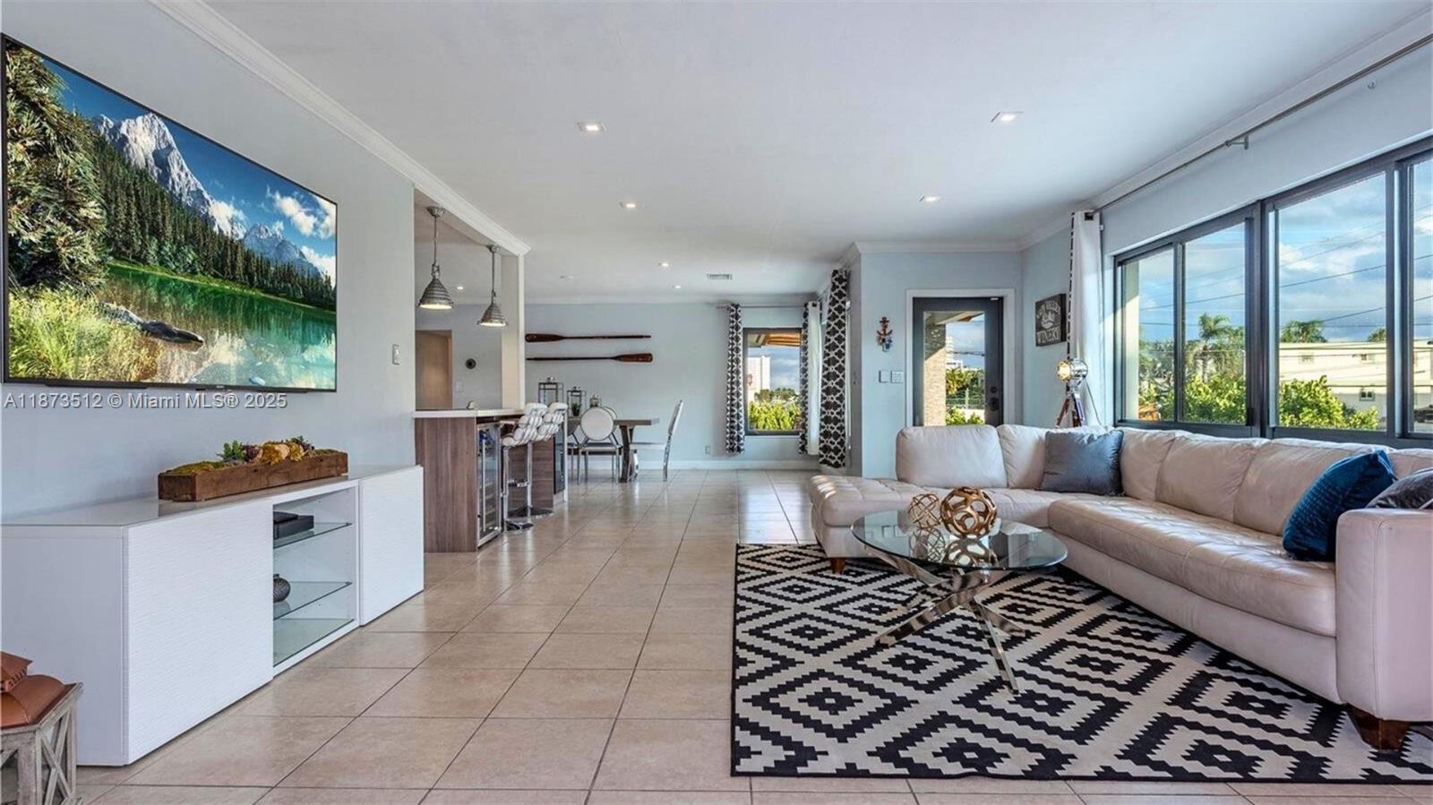 A living room features a large television, a white sectional sofa, and tile flooring — 201 NE 26th Ave, Pompano Beach FL 33062, POMPANO BEACH, FL