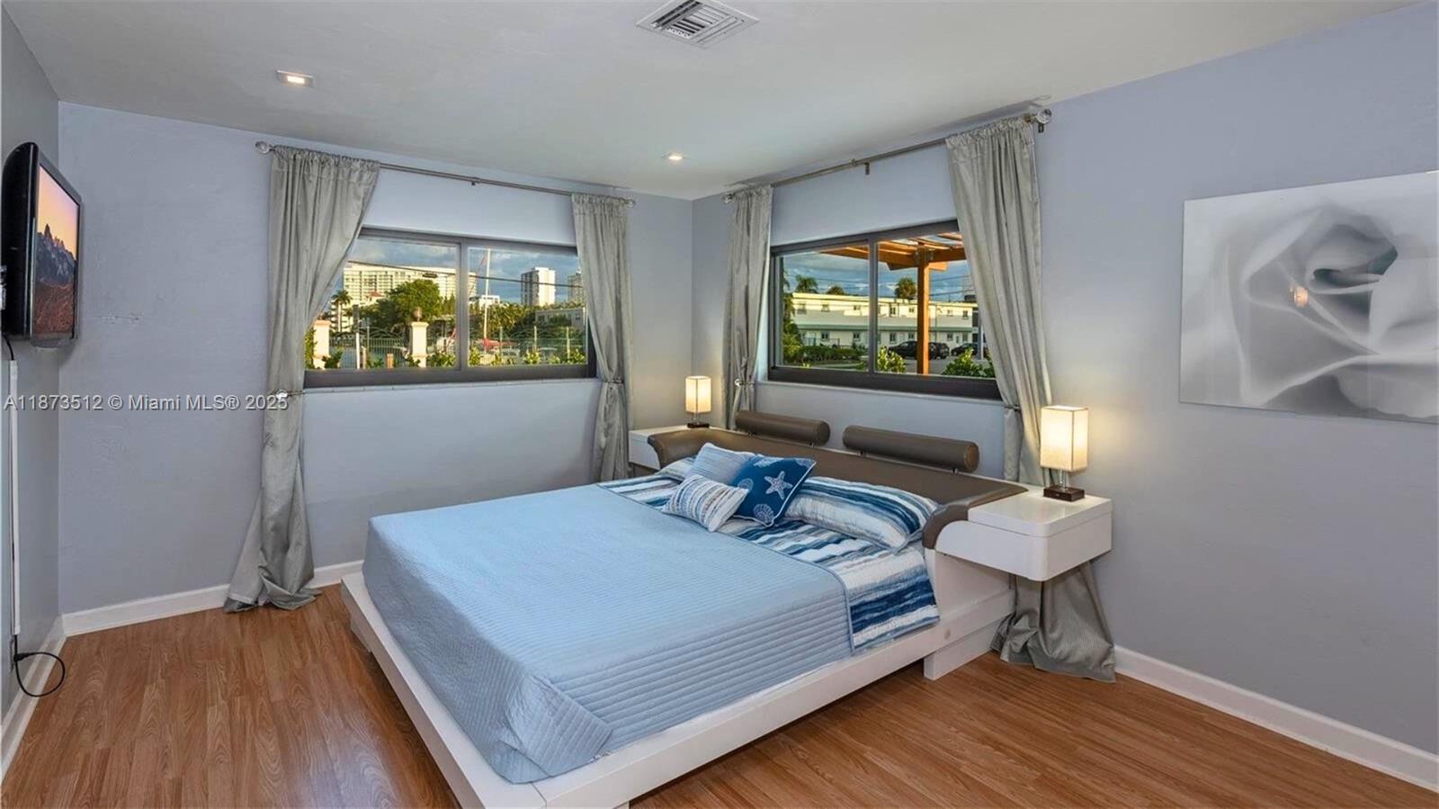 A bedroom features a platform bed, two windows with curtains, and light blue walls — 201 NE 26th Ave, Pompano Beach FL 33062, POMPANO BEACH, FL