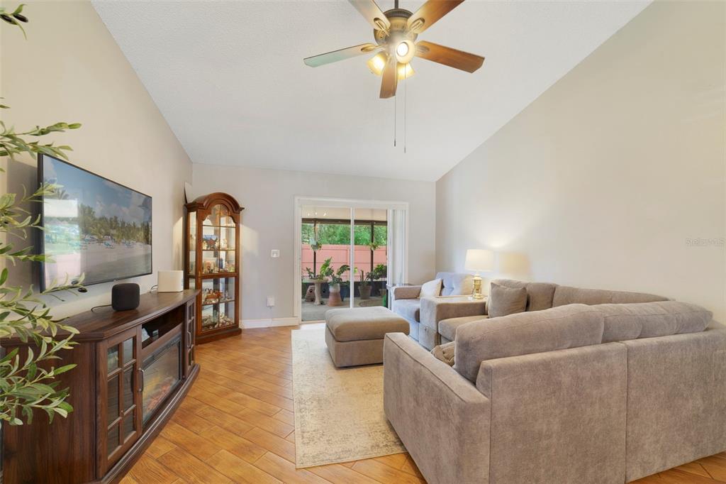 A living room features a grey sectional sofa, wood-look tile flooring, and a sliding glass door — 9478 BRACKIN STREET, ORLANDO, FL