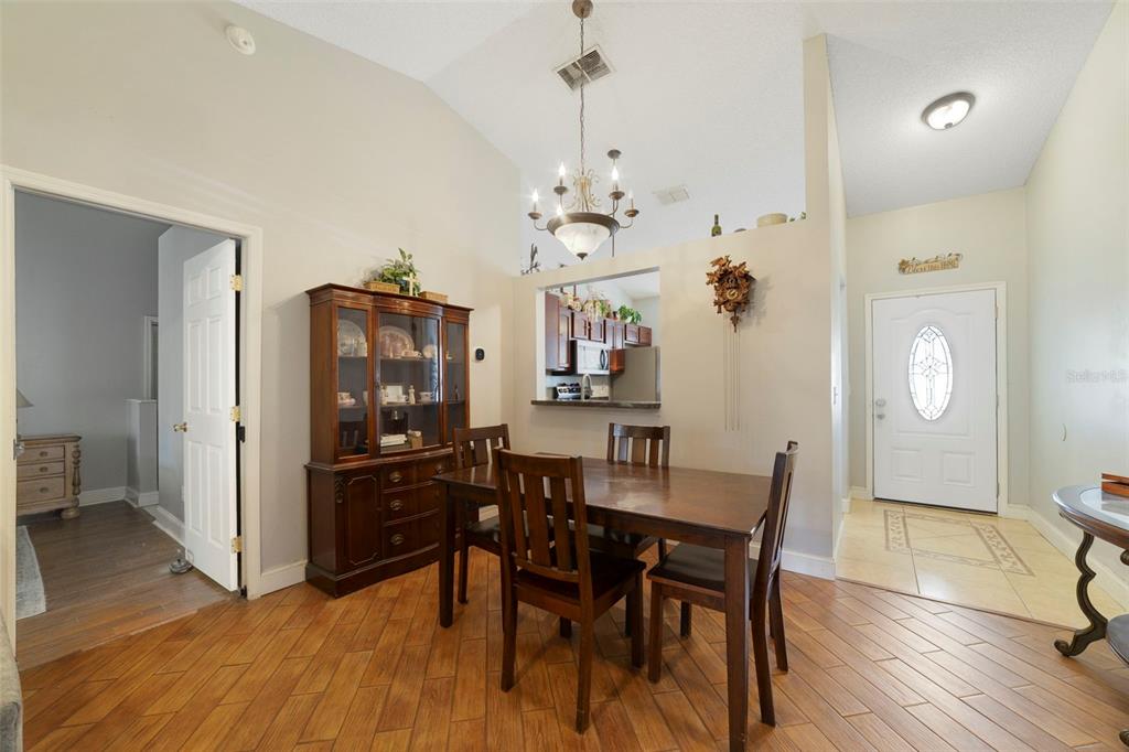 A dining room with a wooden table, hutch, chandelier, and tile flooring near an entryway — 9478 BRACKIN STREET, ORLANDO, FL