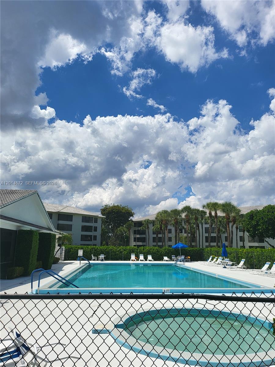 A swimming pool and a circular spa are enclosed by a chain-link fence outdoors — 3640 Whitehall Dr # 406, West Palm Beach FL 33401, WEST PALM BEACH, FL