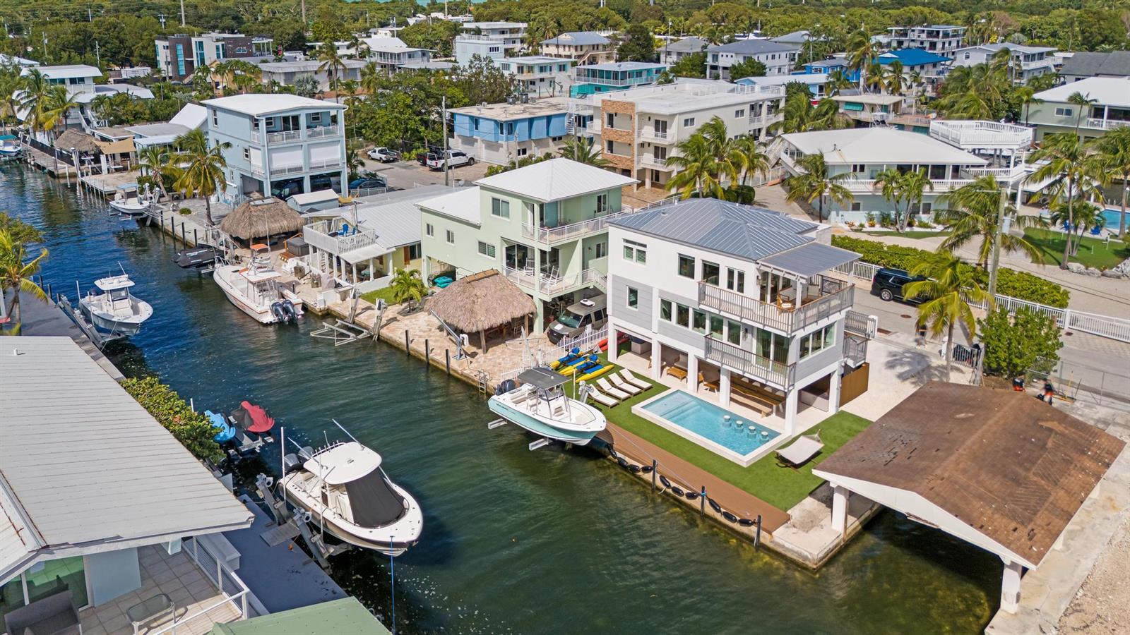 An aerial view shows waterfront homes with private docks, swimming pools, and moored boats — 704 Grouper Lane, Key Largo FL 33037, KEY LARGO, FL