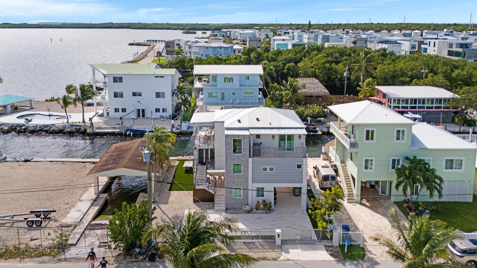 An aerial view shows a multi-story house with a stone facade situated along a canal — 704 Grouper Lane, Key Largo FL 33037, KEY LARGO, FL