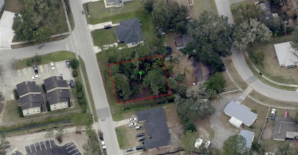 An aerial view shows a rectangular, tree-covered vacant lot outlined in red — 2251 FLORIDA DRIVE, DELTONA, FL