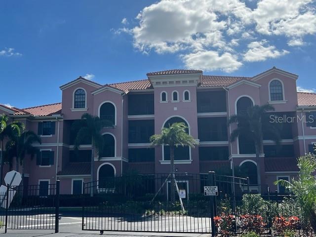 A multi-story pink apartment building with a gated entrance and palm trees under a blue sky — 24417 BALTIC AVENUE UNIT 1102, PUNTA GORDA, FL