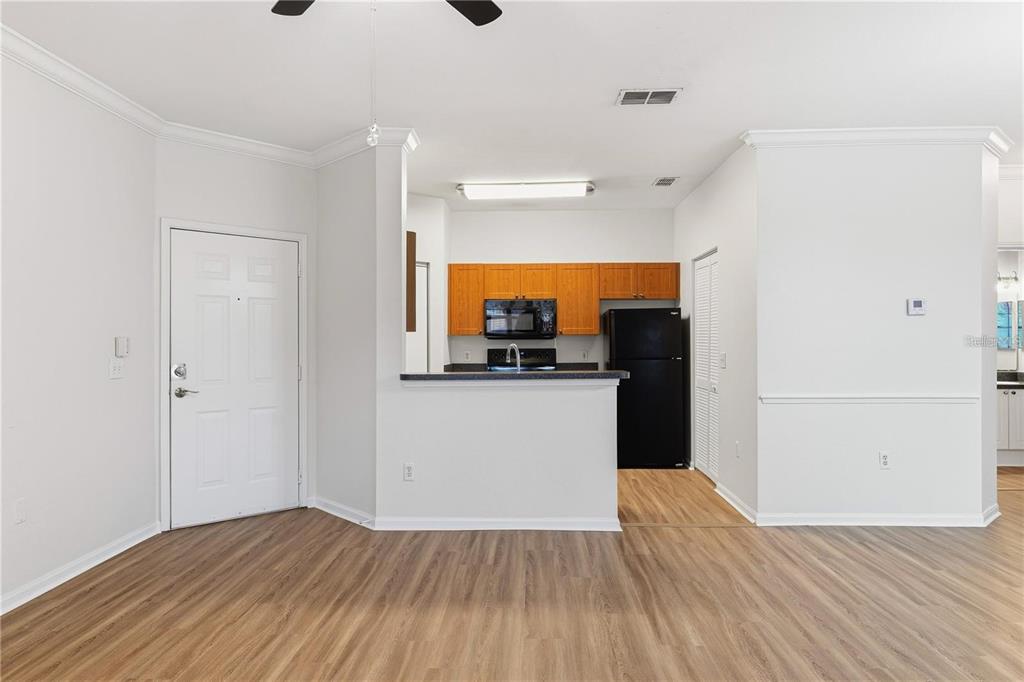 A view of an open-concept kitchen with wood cabinets and black appliances from a living area — 2249 PORTOFINO PLACE UNIT 22-2217, PALM HARBOR, FL