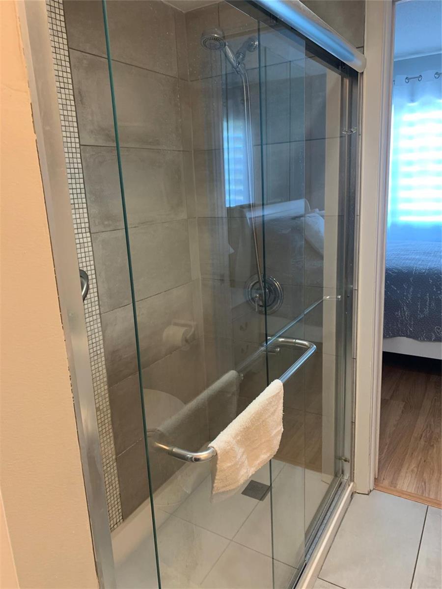 A glass-enclosed shower with gray tiled walls and a chrome handheld showerhead — 2751 Golf Boulevard # 2028, Pompano Beach FL 33064, POMPANO BEACH, FL
