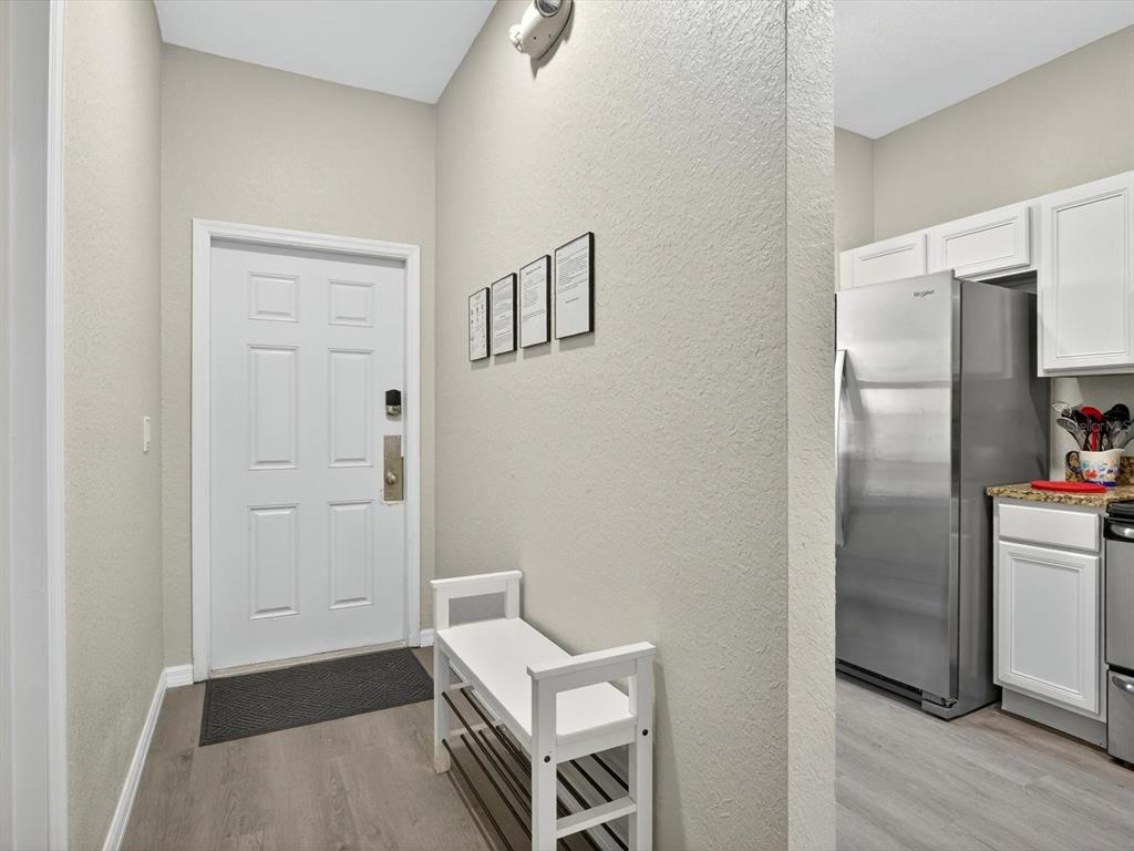 An entryway features a white door, a shoe bench, and a view into a kitchen — 3948 CALABRIA AVENUE, DAVENPORT, FL