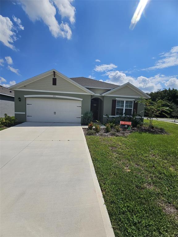 A single-story house with a white garage door, light green siding, and a front lawn — 975 BROOKLET DRIVE, DAVENPORT, FL