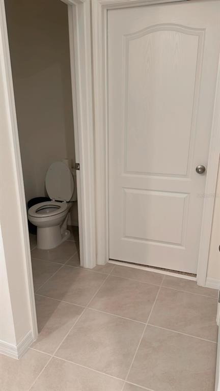 A white toilet sits in a small room next to a closed white interior door — 975 BROOKLET DRIVE, DAVENPORT, FL