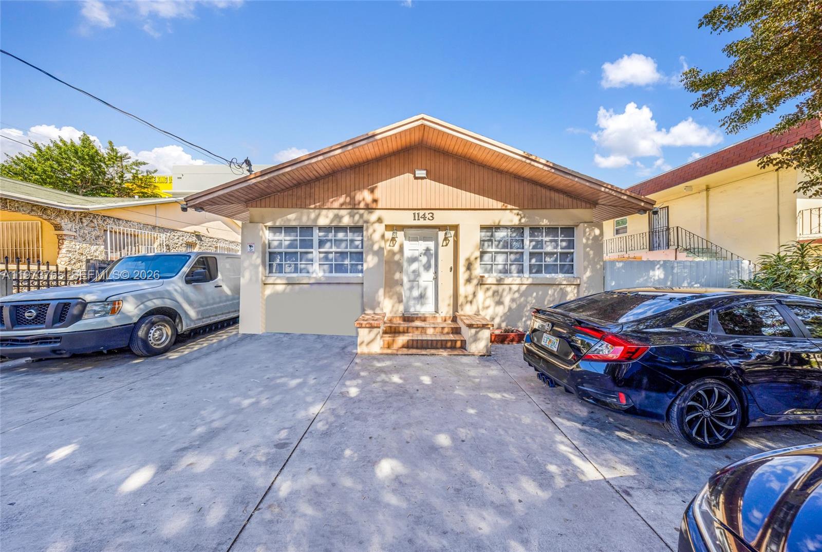 A single-story house with a concrete driveway, two parked vehicles, and a gabled roof — 1143 NW 6th St, Miami FL 33136, MIAMI, FL