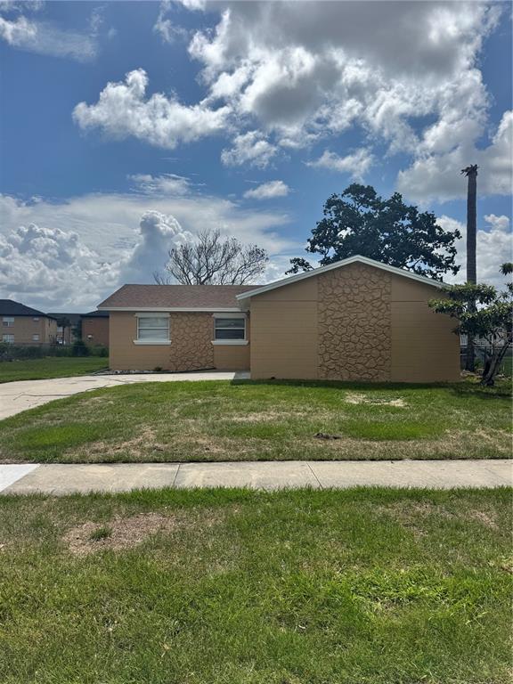 A single-story house with tan siding, stone accents, and a brown shingled roof — 5693 TULIP AVENUE, ORLANDO, FL