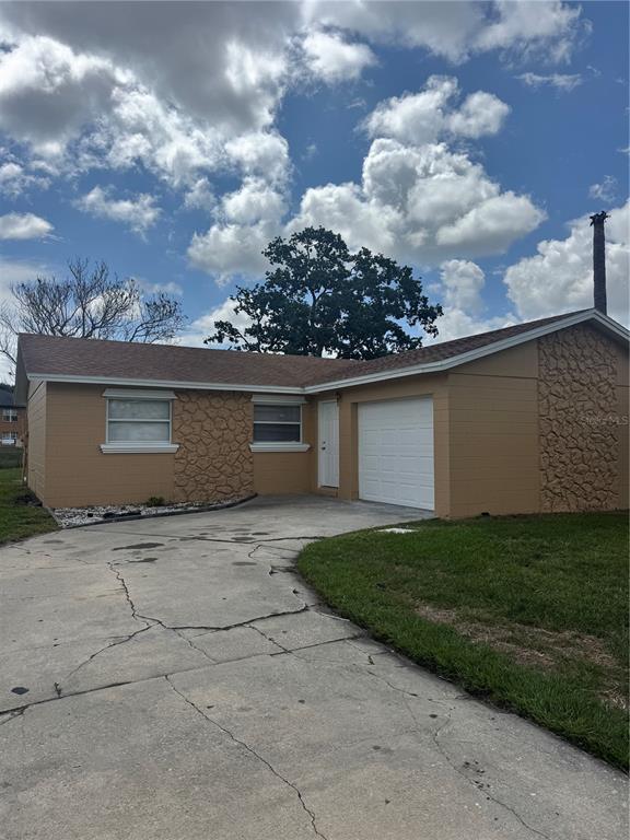 A single-story house with tan painted brick, stone accents, and a concrete driveway — 5693 TULIP AVENUE, ORLANDO, FL