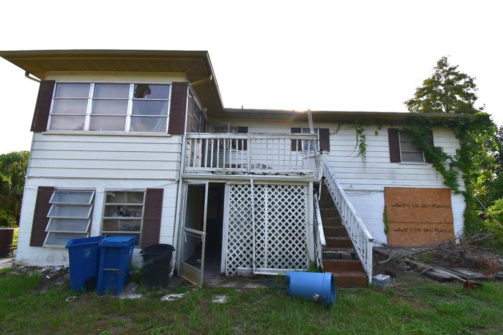 A two-story house with a wooden deck, exterior staircase, and boarded-up windows in the backyard — 613 CHESTNUT STREET, OLDSMAR, FL