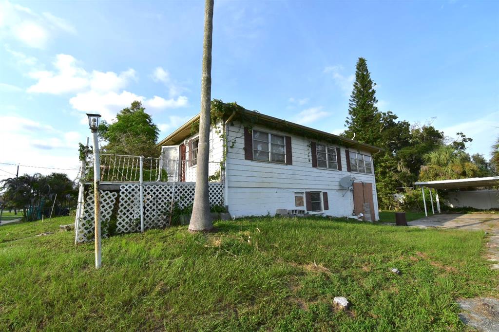 A white, two-story house with a raised wooden deck and a detached carport — 613 CHESTNUT STREET, OLDSMAR, FL
