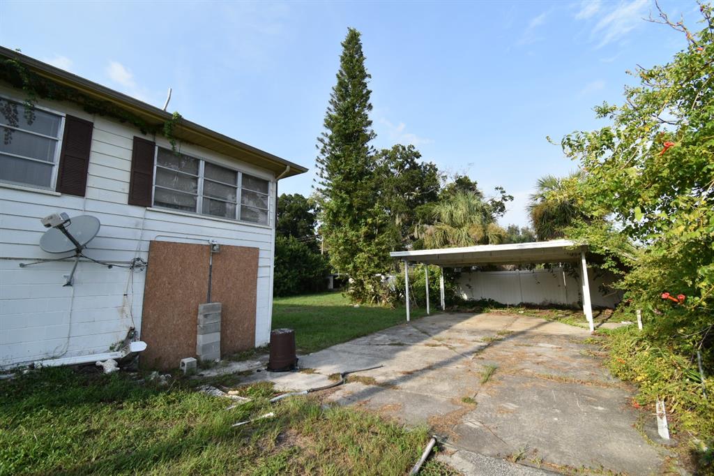 A white house with a carport and a large, tall pine tree in the yard — 613 CHESTNUT STREET, OLDSMAR, FL