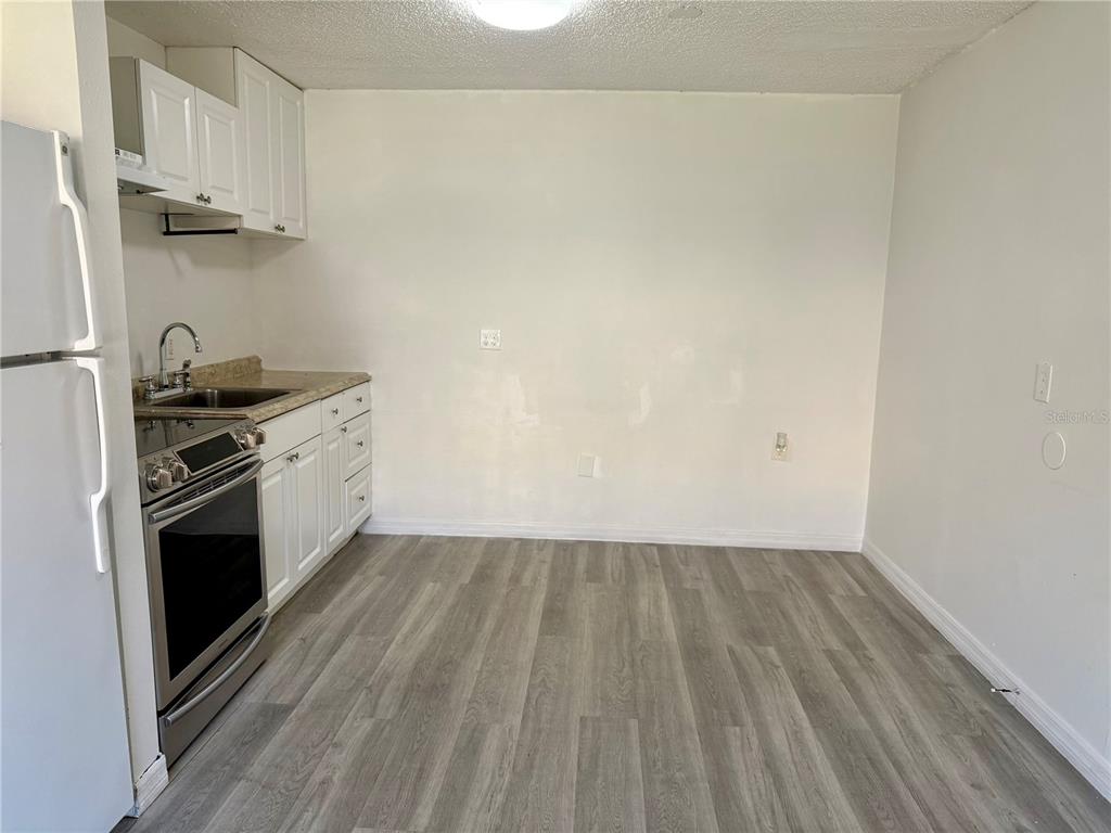 A kitchen features white cabinets, stainless steel appliances, a sink, and gray wood-look flooring — 9013 WESTCHESTER CIRCLE UNIT 32, TAMPA, FL