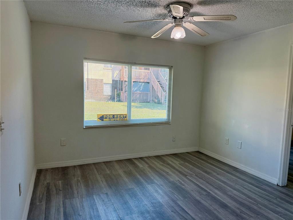 An empty bedroom features light gray wood-look flooring, white walls, and a ceiling fan — 9013 WESTCHESTER CIRCLE UNIT 32, TAMPA, FL