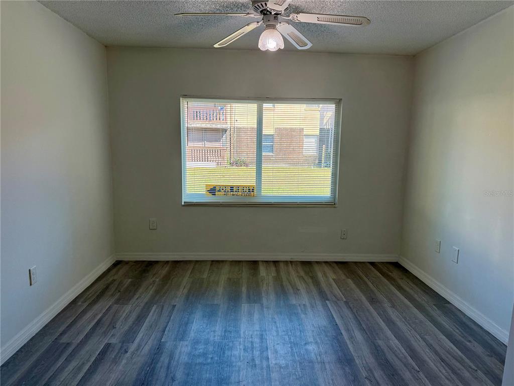 An empty bedroom features light gray walls, wood-look vinyl flooring, and a ceiling fan — 9013 WESTCHESTER CIRCLE UNIT 32, TAMPA, FL