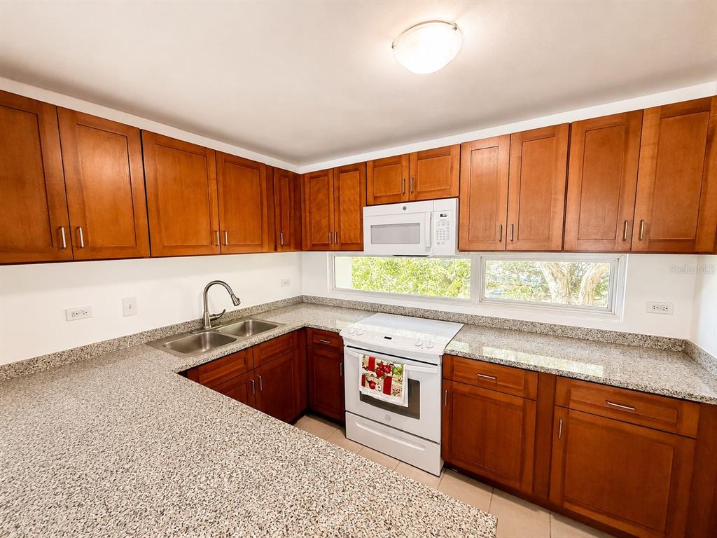 A kitchen features wood cabinets, granite countertops, a double sink, and white appliances — 1554 CALLE LÓPEZ LANDRÓN apt #301, SAN JUAN, PR