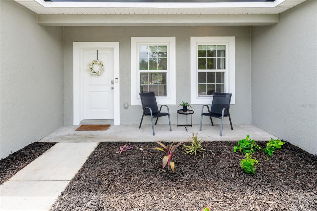 A front porch features a white door, two windows, and two chairs with a small table — 13669 SW 81ST CIRCLE, OCALA, FL