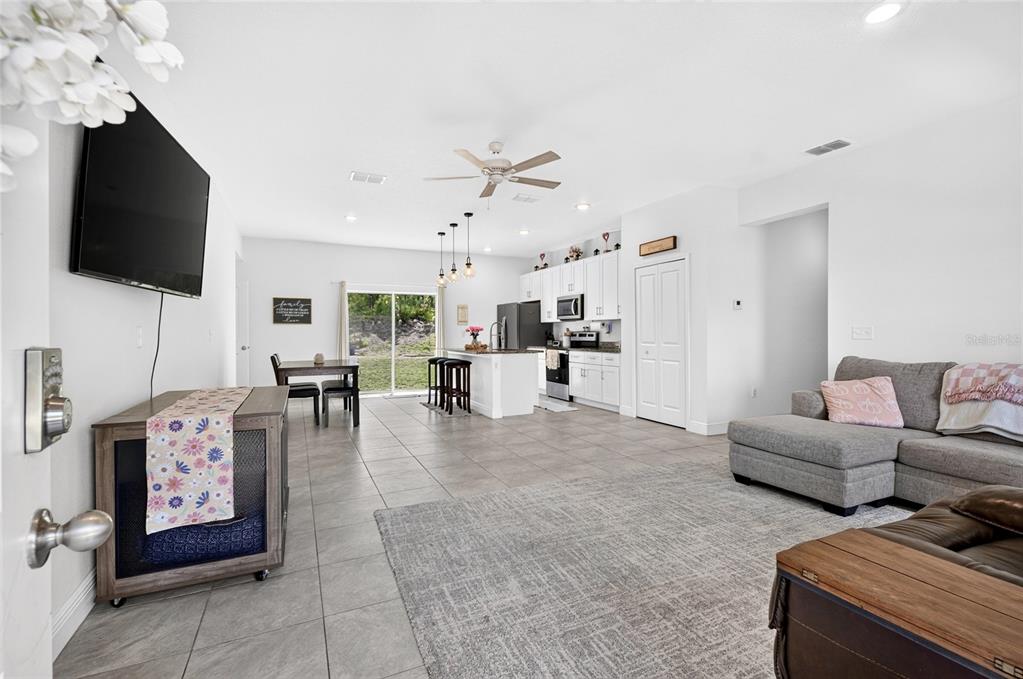 An open-concept living area features a kitchen with white cabinets, tile floors, and a sofa — 13669 SW 81ST CIRCLE, OCALA, FL