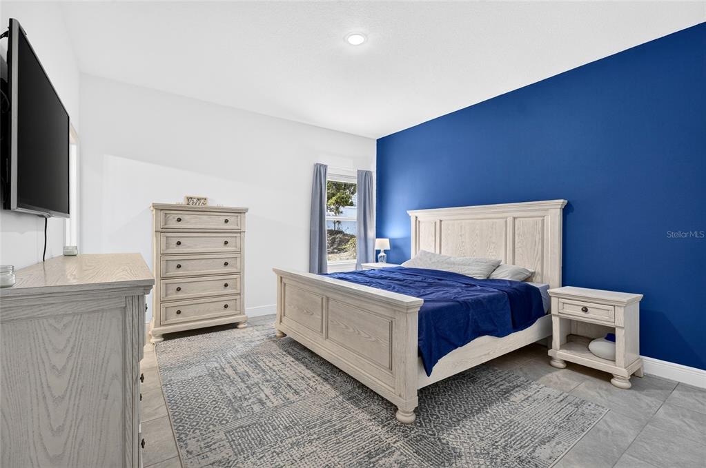 A bedroom features a blue accent wall, light wood furniture, and a patterned area rug — 13669 SW 81ST CIRCLE, OCALA, FL