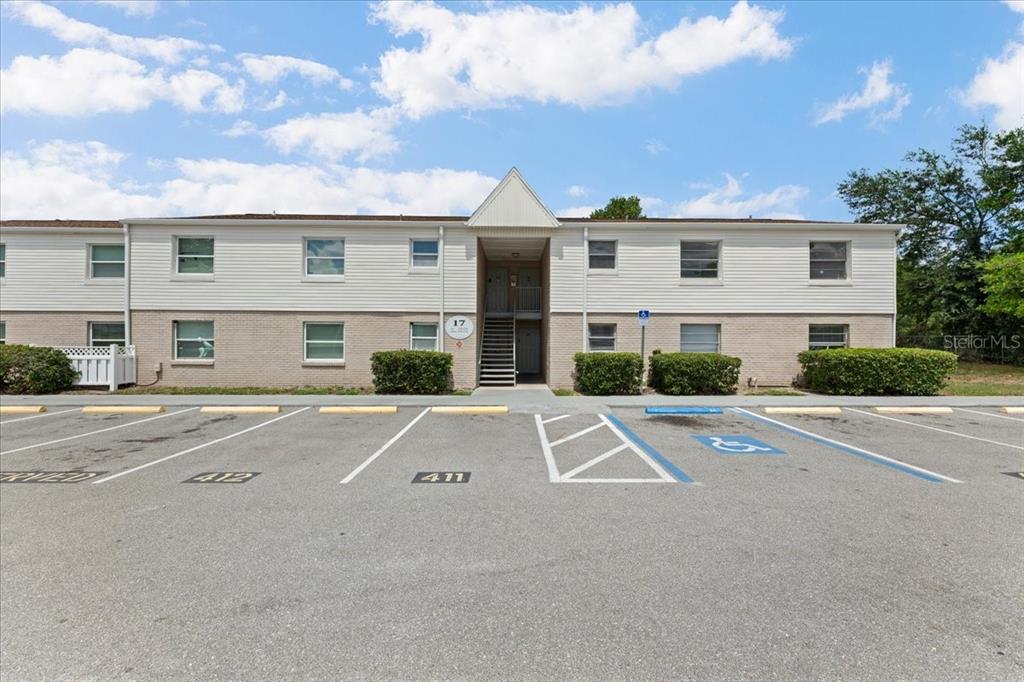 A two-story apartment building features white siding, brick lower walls, and a central staircase — 7210 N MANHATTAN AVENUE UNIT 1714, TAMPA, FL