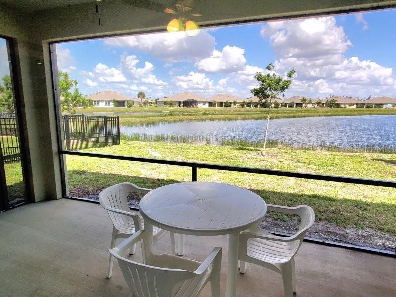 A screened-in patio features a white table and chairs overlooking a pond and neighborhood houses — 7104 W LENOX CIRCLE, PUNTA GORDA, FL