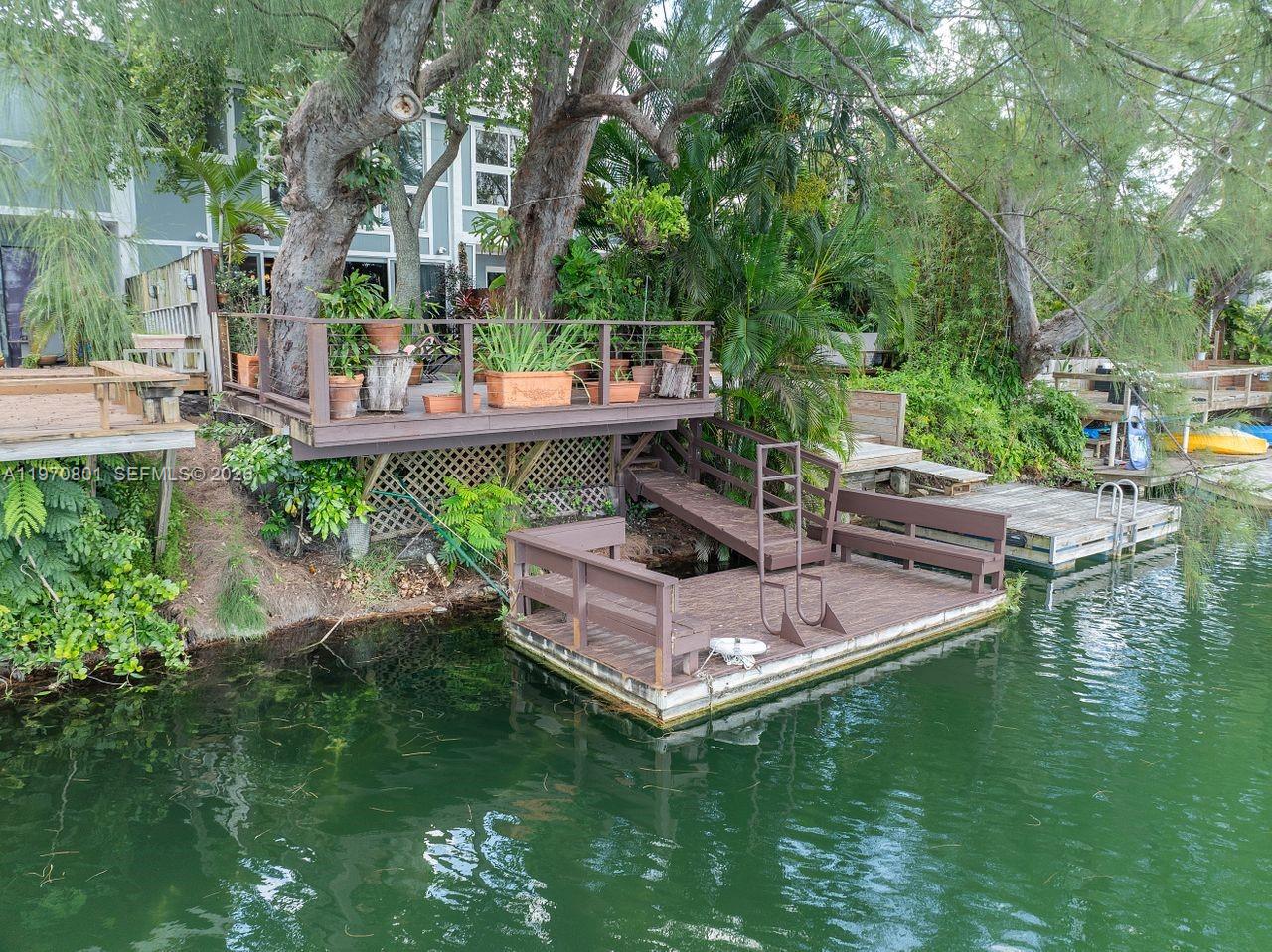 A wooden deck and floating dock sit along a canal next to a house — 4905 SW 71st Pl, Miami FL 33155, MIAMI, FL