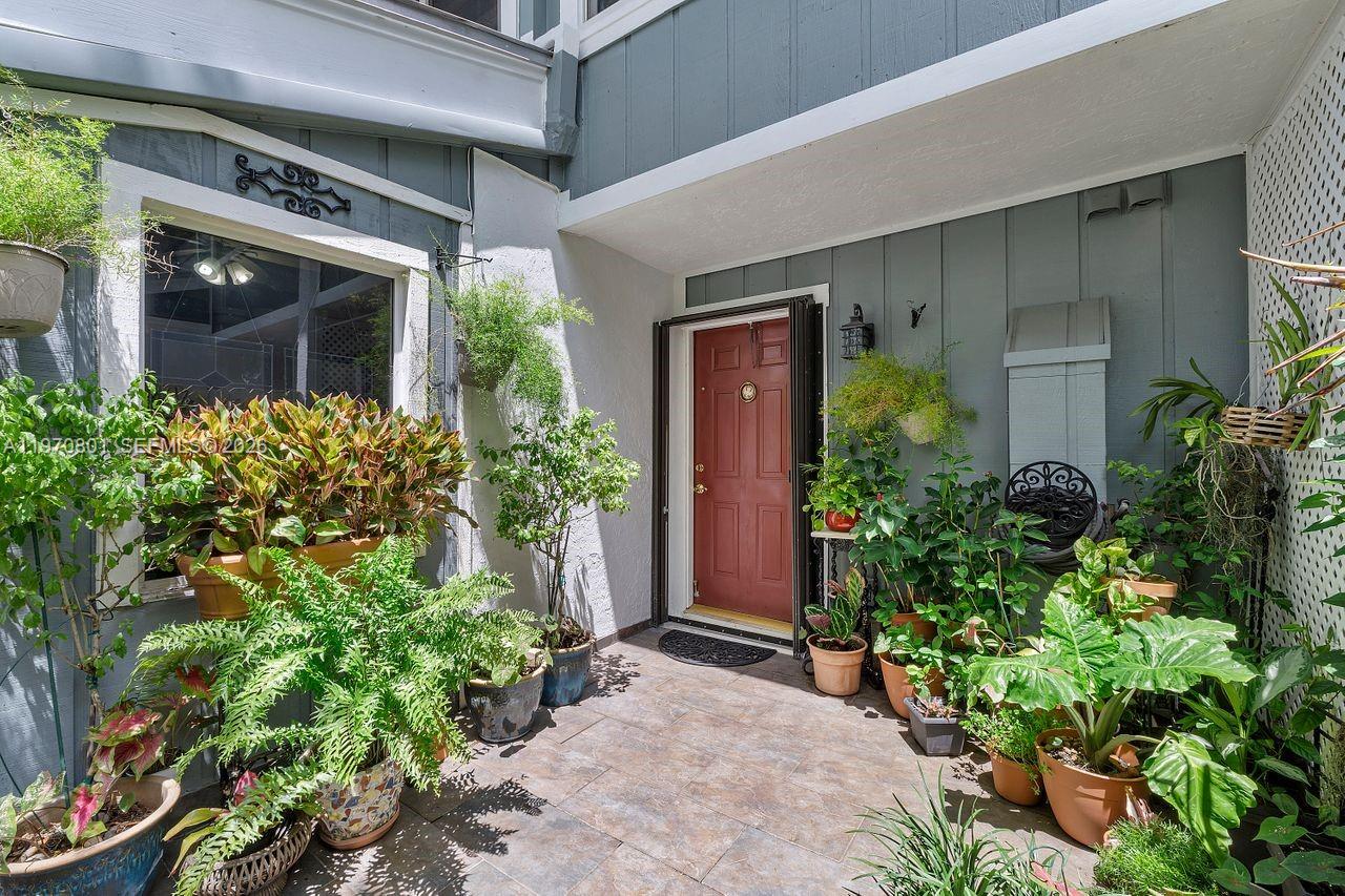 A front entryway features a red door, tiled patio, and numerous potted plants — 4905 SW 71st Pl, Miami FL 33155, MIAMI, FL