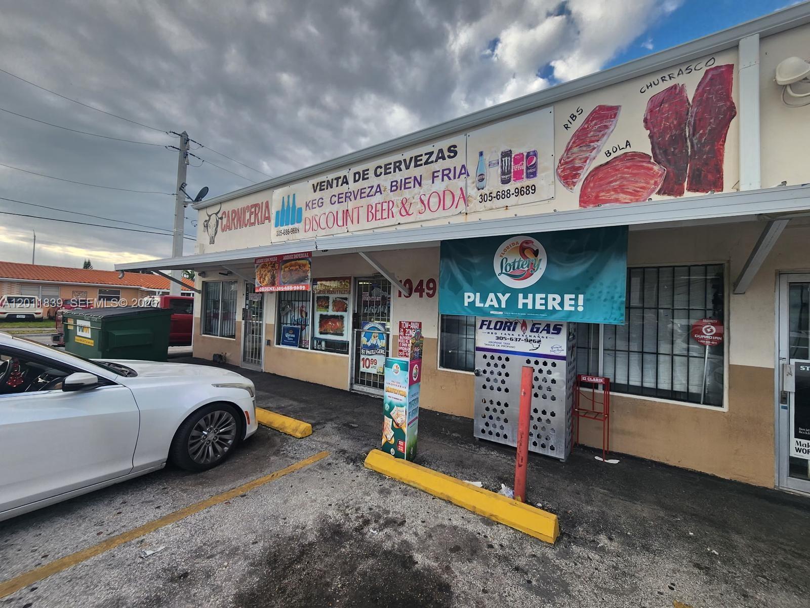 The exterior of a commercial building features signage for a butcher shop and lottery sales — 4125 E 10th Ct, Hialeah FL 33013, HIALEAH, FL