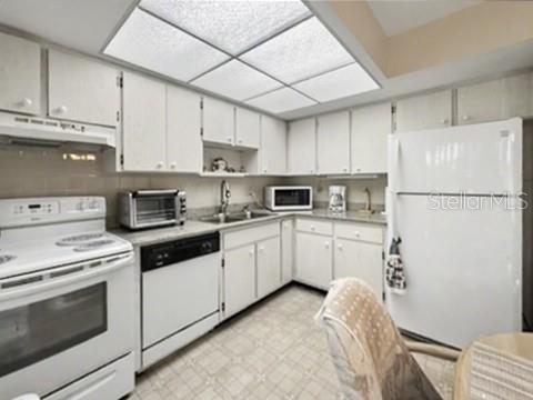 A kitchen with white cabinets, white appliances, a drop ceiling, and light-colored vinyl flooring — 12 QUAILS RUN BOULEVARD UNIT 7, ENGLEWOOD, FL
