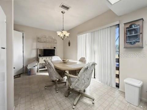 A dining area features a round table with four chairs, a chandelier, and sliding glass doors — 12 QUAILS RUN BOULEVARD UNIT 7, ENGLEWOOD, FL