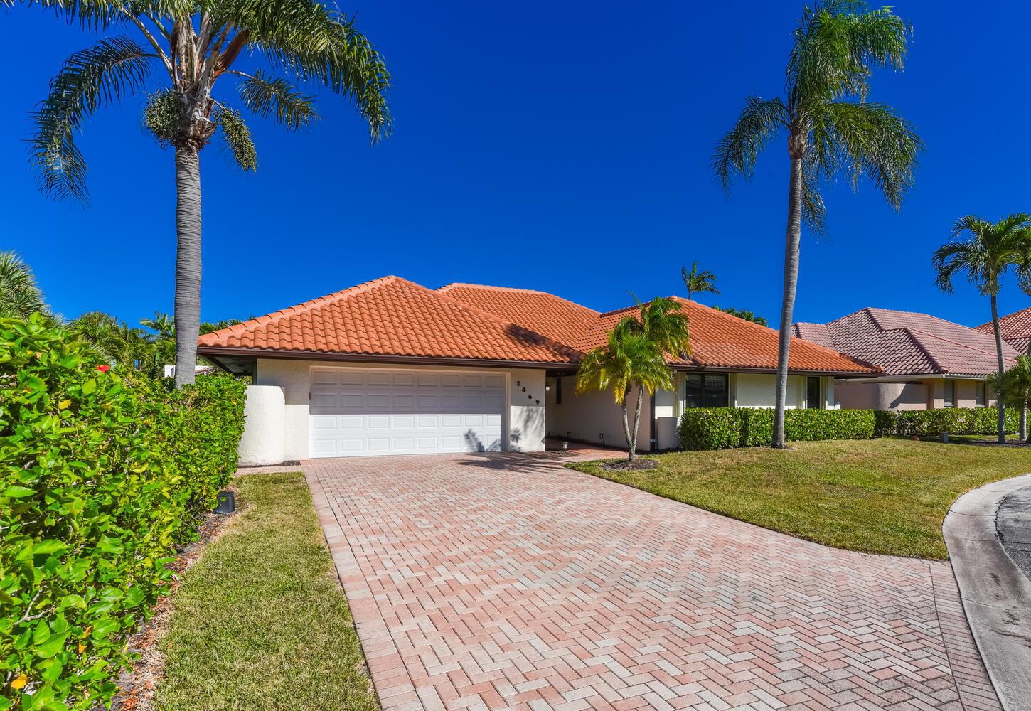 A single-story house with a red tile roof, white garage, and brick driveway — 1469 Vía Privada, Jupiter FL 33477, JUPITER, FL