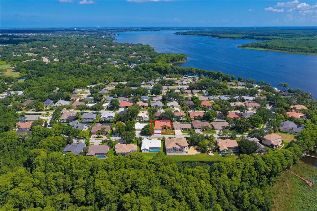 An aerial view shows a residential neighborhood with a highlighted house near a large lake — 3909 TARIAN COURT, PALM HARBOR, FL
