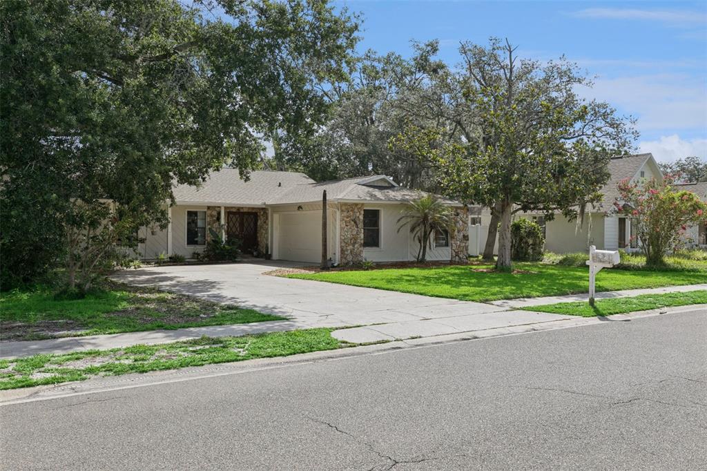 A single-story house with a stone facade, a concrete driveway, and a large front lawn — 773 COACH LIGHT DRIVE, CASSELBERRY, FL