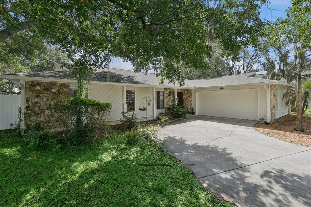 A single-story house with stone accents, light-colored siding, a two-car garage, and a concrete driveway — 773 COACH LIGHT DRIVE, CASSELBERRY, FL