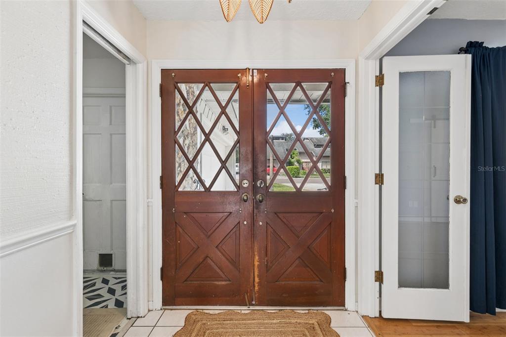 A foyer features double wooden front doors with diamond-patterned glass panes and tiled flooring — 773 COACH LIGHT DRIVE, CASSELBERRY, FL