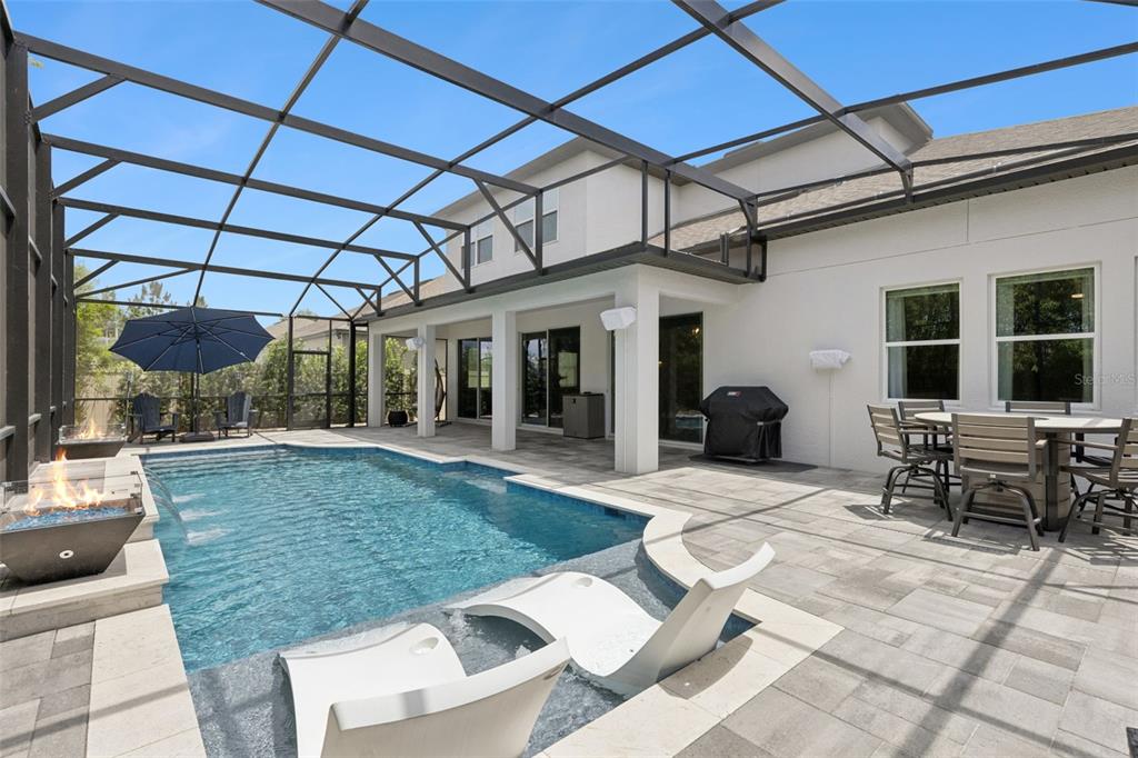 A screened-in patio features a swimming pool with lounge chairs and a fire feature — 3336 LONE CYPRESS POINT, OVIEDO, FL