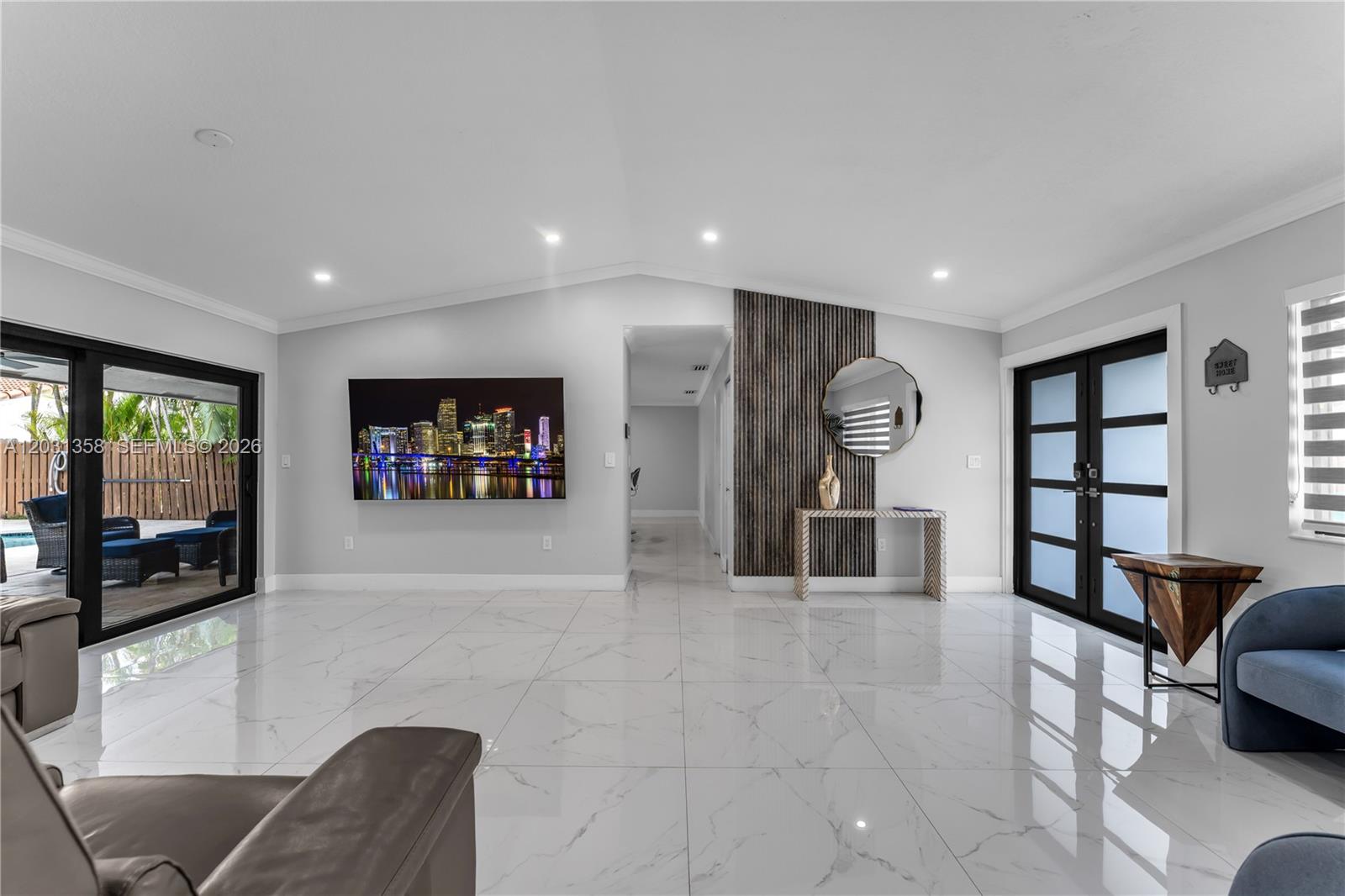 A bright living room features white marble floors, a wall-mounted television, and a wood-slat accent wall — 15842 SW 105th St, Miami FL 33196, MIAMI, FL