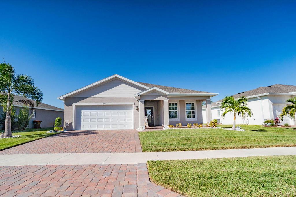 A single-story suburban house with a paved driveway, two-car garage, and a manicured lawn — 4198 Keeson Circle, Vero Beach FL 32967, VERO BEACH, FL