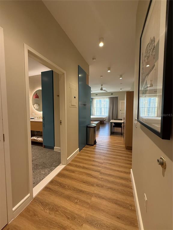 A hallway with wood-look flooring leads to a bedroom and a bathroom with blue cabinetry — 3151 SUNSET WALK DR UNIT 516, KISSIMMEE, FL