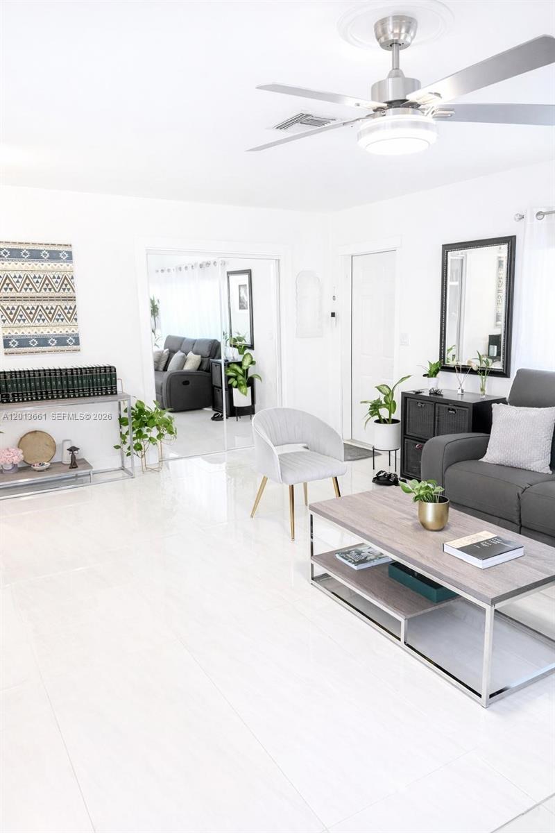 A bright living room features white tile floors, a gray sofa, and a ceiling fan — 1001 NE 10th St # 2, Hallandale Beach FL 33009, HALLANDALE BEACH, FL