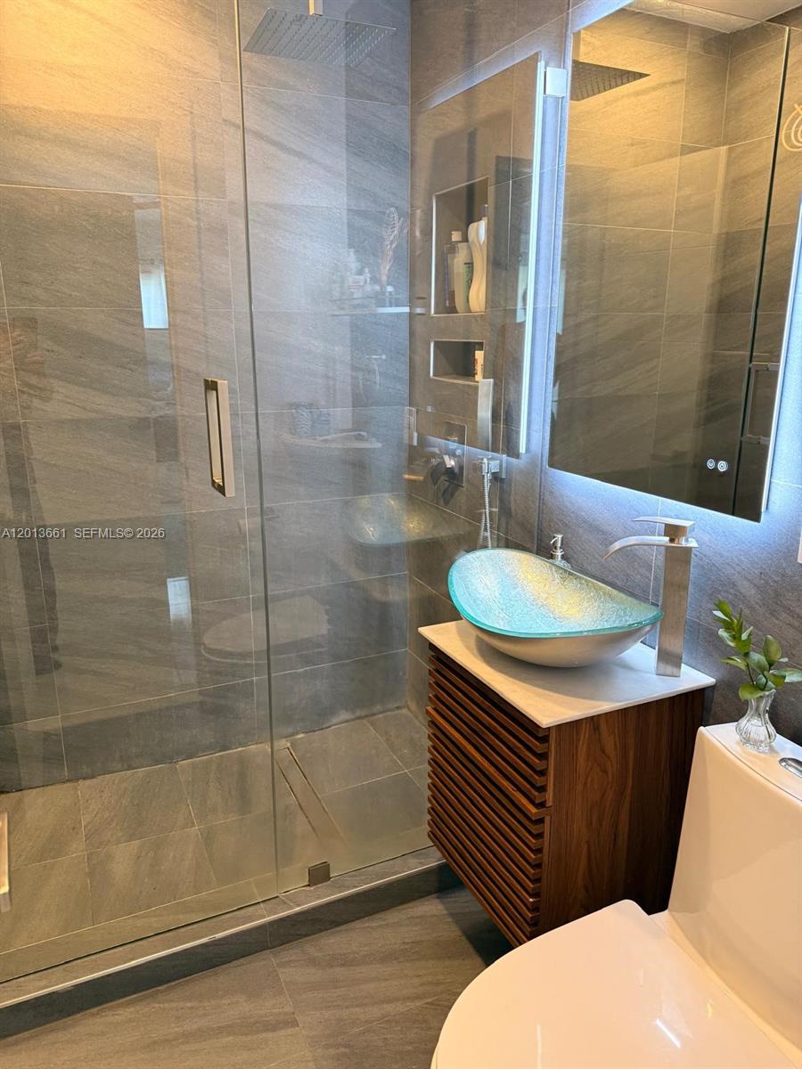 A modern bathroom features a glass vessel sink, a slatted wood vanity, and a walk-in shower — 1001 NE 10th St # 2, Hallandale Beach FL 33009, HALLANDALE BEACH, FL