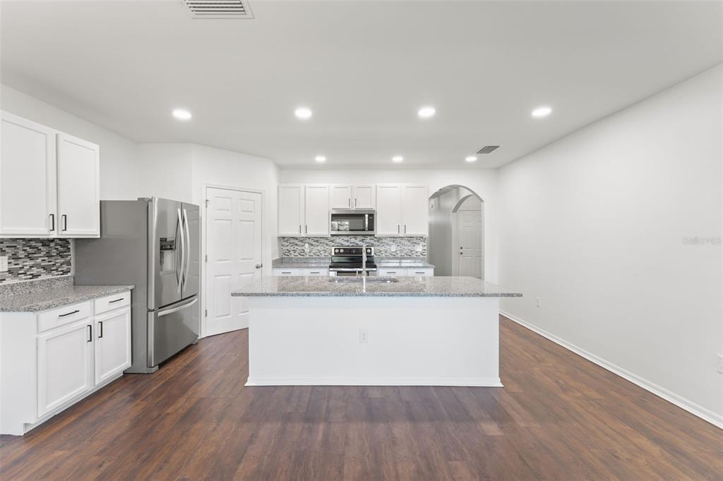 A kitchen features white cabinets, granite countertops, stainless steel appliances, and a central island — 3945 RIVER BANK WAY, PUNTA GORDA, FL