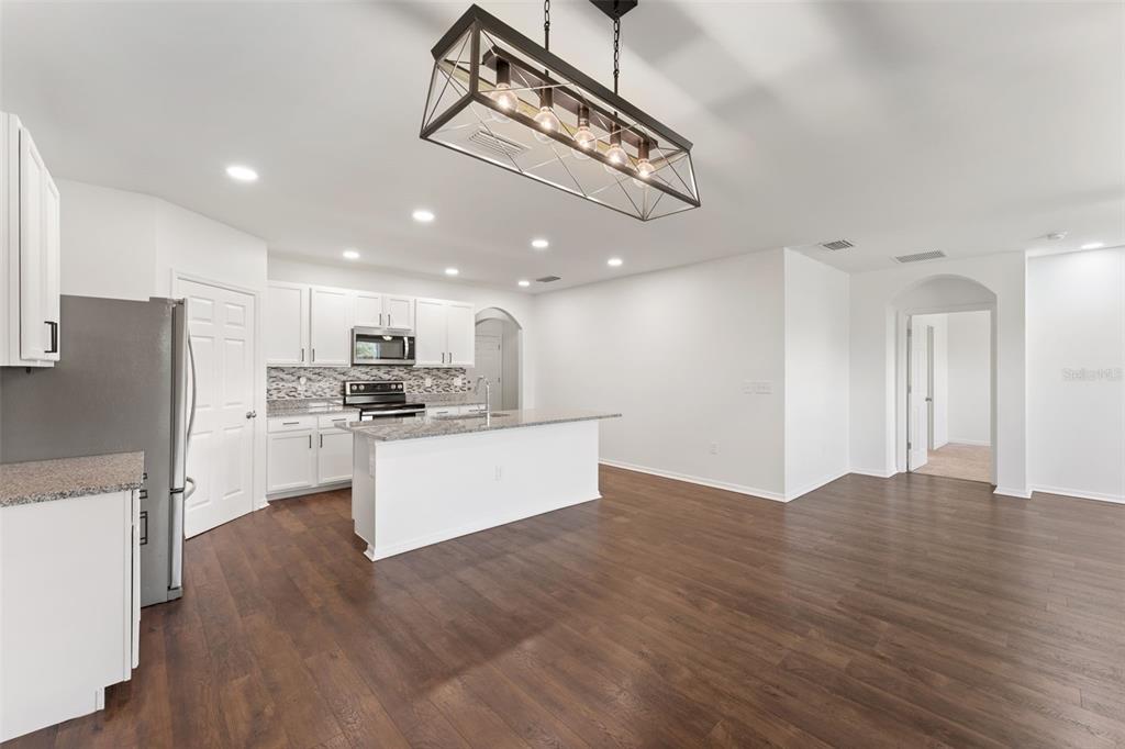 A modern kitchen features white cabinets, granite countertops, a center island, and dark wood flooring — 3945 RIVER BANK WAY, PUNTA GORDA, FL