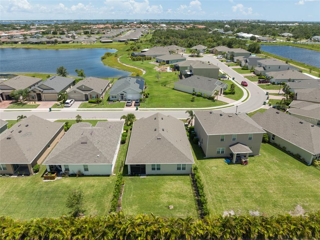 An aerial view shows suburban houses with backyards and a nearby lake — 3945 RIVER BANK WAY, PUNTA GORDA, FL